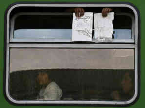 Seit Stunden harren die Flüchtlinge in dem Zug aus. Sie bekommen keine Informationen und versuchen mit Zetteln auf sich aufmerksam zu machen. Foto: picture-alliance/dpa