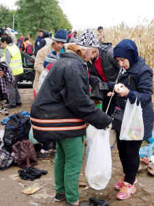 Bei ihren Zwischenstopps an den Grenzen werden die Menschen von Freiwilligen versorgt. Sie bekommen etwas zu essen und warme Kleidung. Den Menschen bleibt wenig Zeit, die Gaben zu verstauen. Foto: BR | Srdjan Govedarica