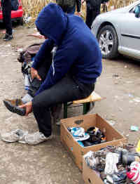 Einige der Flüchtlinge sind schon seit Wochen unterwegs. Weite Strecken davon zu Fuß. Es wundert nicht, dass sie neues Schuhwerk dankend annehmen. Hier im Niemandsland zwischen Serbien und Kroatien haben Helfer gespendete Schuhe am Straßenrand abgelegt. Die Flüchtlinge können sich bedienen. Foto: BR | Srdjan Govedarica