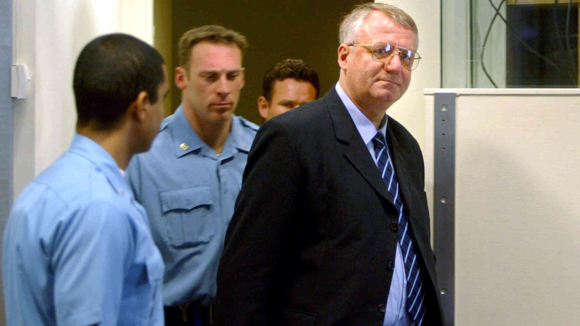 Vojislav Seselj (re.) wird am 26.2.2003 von Gerichtsbeamten erstmals vor das UN-Kriegsverbrecher-Tribunal in Den Haag gebracht. Er hat vor dem Tribunal die Bestellung eines Verteidigers abgelehnt - der promovierte Jurist verteidigt sich selbst. Foto: picture-alliance | dpa