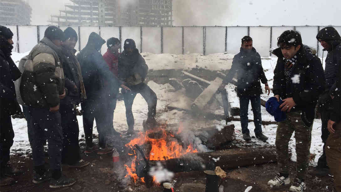 Flüchtlinge stehen am 09.01.2017 in Belgrad am Rande des Zentrums bei Eiseskälte vor einem leerstehenden Lagergebäude unweit einer Baustelle an einem Lagerfeuer. Foto: picture-alliance | dpa