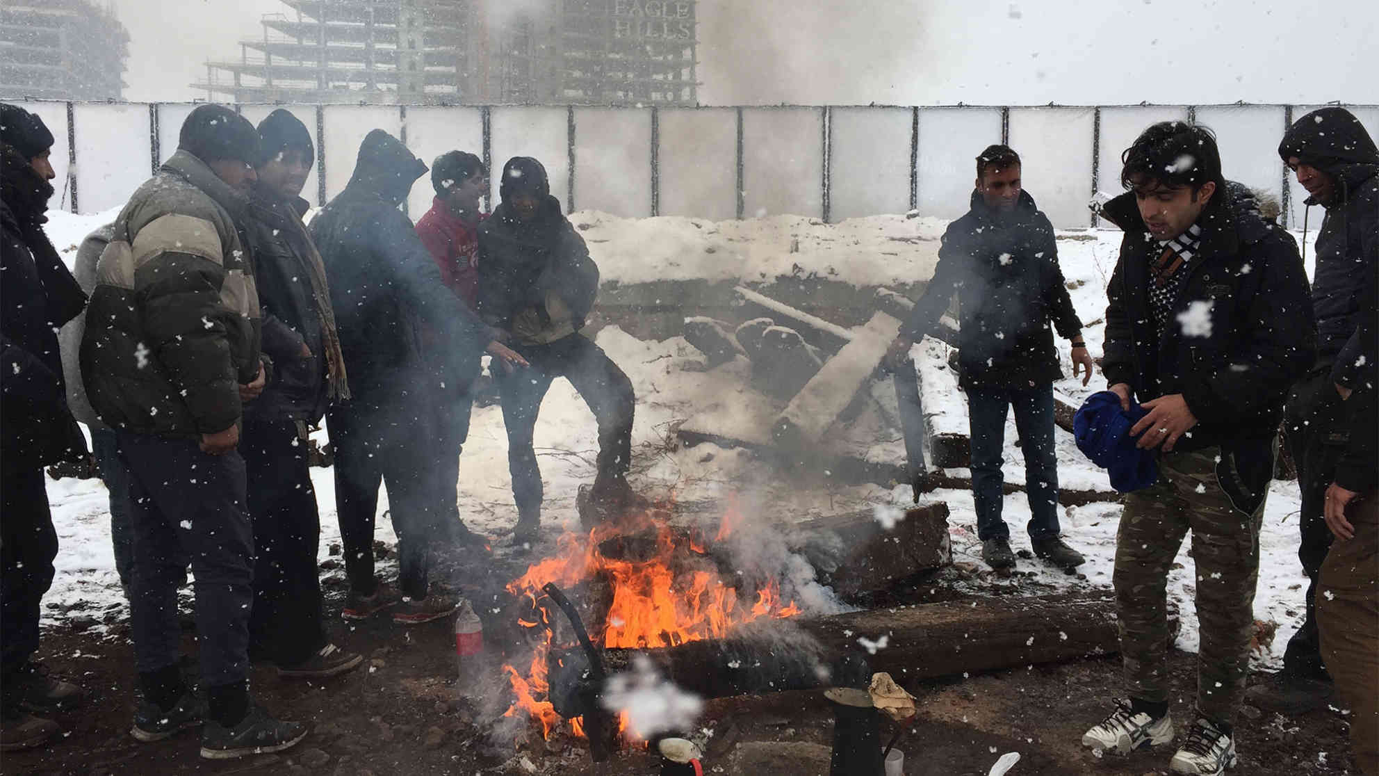Flüchtlinge stehen am 09.01.2017 in Belgrad am Rande des Zentrums bei Eiseskälte vor einem leerstehenden Lagergebäude unweit einer Baustelle an einem Lagerfeuer. Foto: picture-alliance | dpa