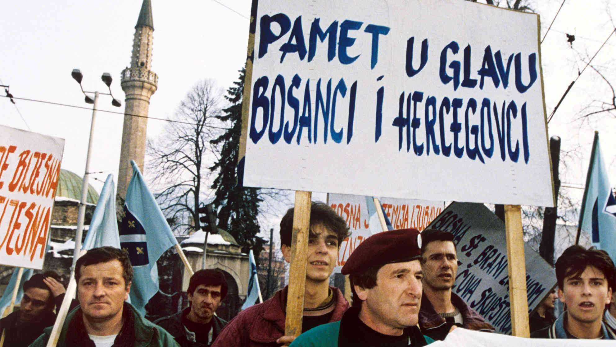 Demonstranten mit einem Plakat auf dem geschrieben steht 'Seid schlau, Bosnier und Herzegowiner' am 27.02.1992 in den Straßen von Sarajevo. Am 29.02./01.03. wurde in einem Referendum für die Unabhängigkeit gestimmt. Foto: picture-alliance | dpa