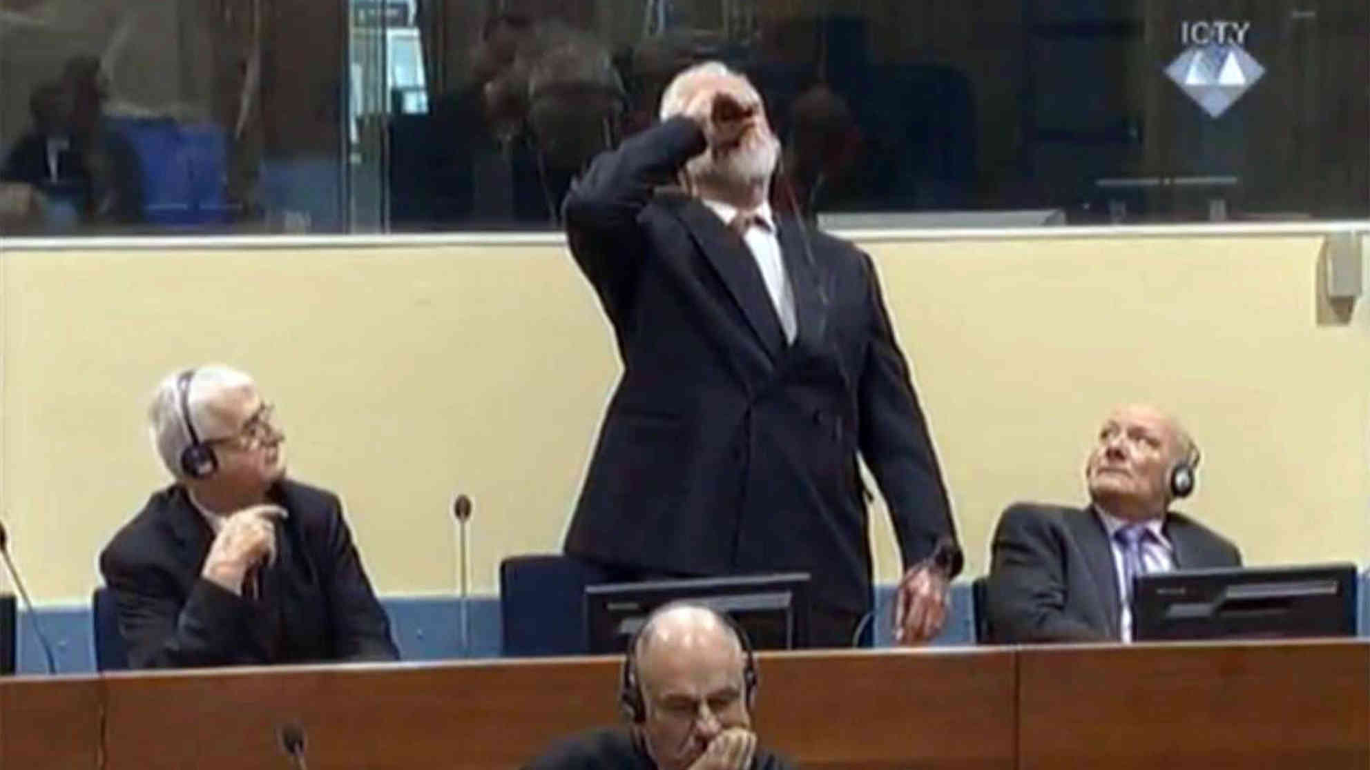 Slobodan Praljak trinkt im Gerichtssaal in Den Haag eine noch unbekannte Flüssigkeit, bricht zusammen und stirbt später im Krankenhaus. Foto: picture alliance | AA