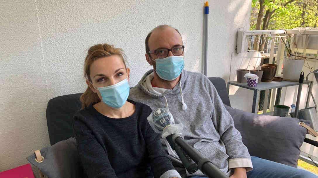Das Ehepaar Milijana und Aleksandar Karganovic auf ihrem Balkon, die während des Interviews Gesichtsmasken tragen. Sie ist Architektin und ist seit mehreren Wochen im Homeoffice. Er ist Bauingenieur und fährt werktags in sein Büro, von 7 Uhr bis 13 Uhr. Foto: BR | Dejan Stefanovic