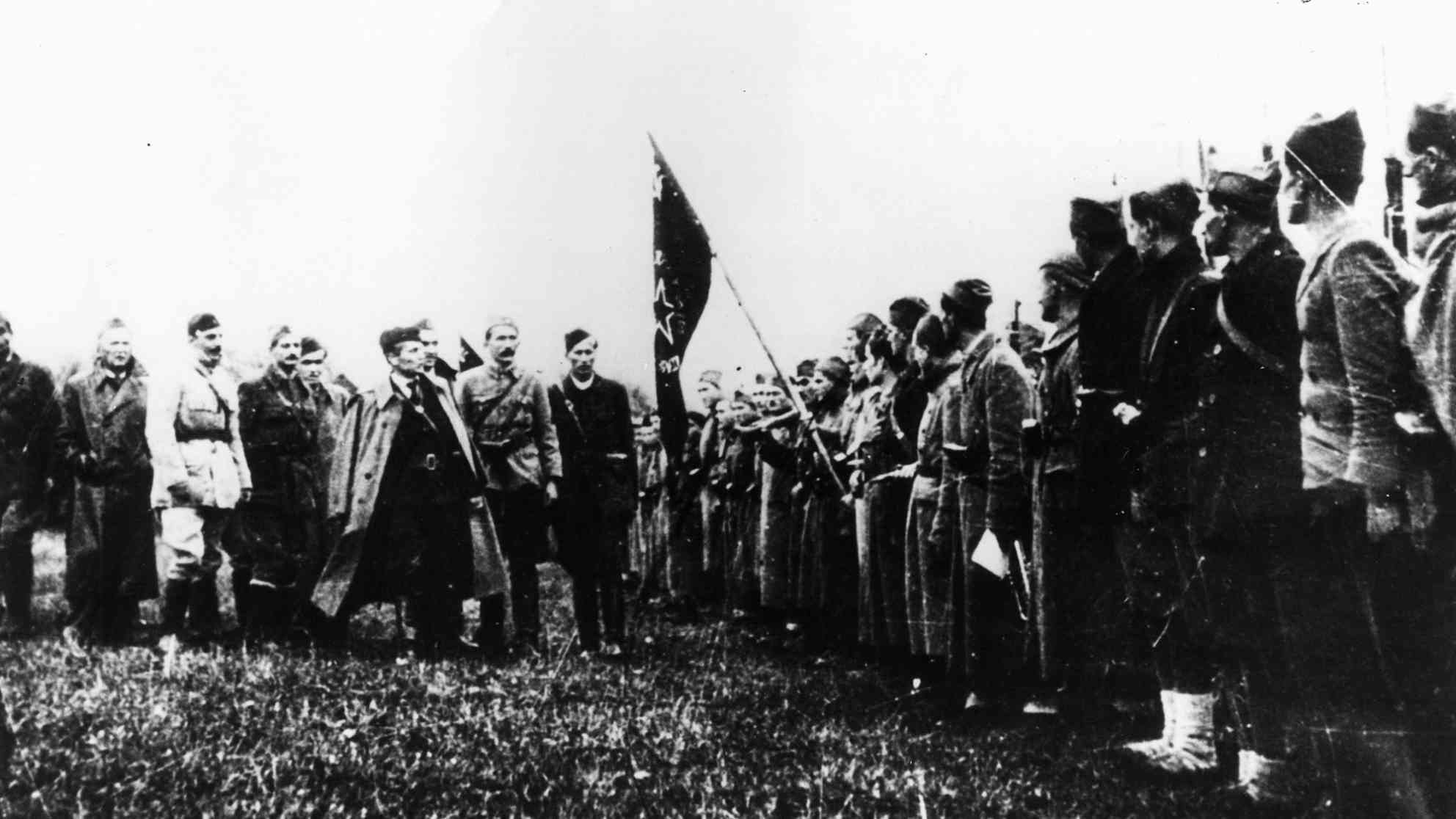 Josip Broz Tito (Mitte mit umgelegtem Mantel) als Kommandeur der Nationalen Freiheitskräfte übergibt das Banner an die erste Proletarier-Brigade am 7. November 1942 in Bosanski Petrovac. Archivfoto: picture-alliance | akg-images